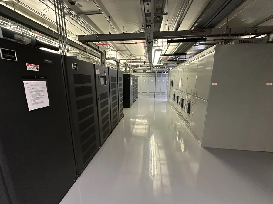 Row of Vertiv UPS modules facing their output switchgear