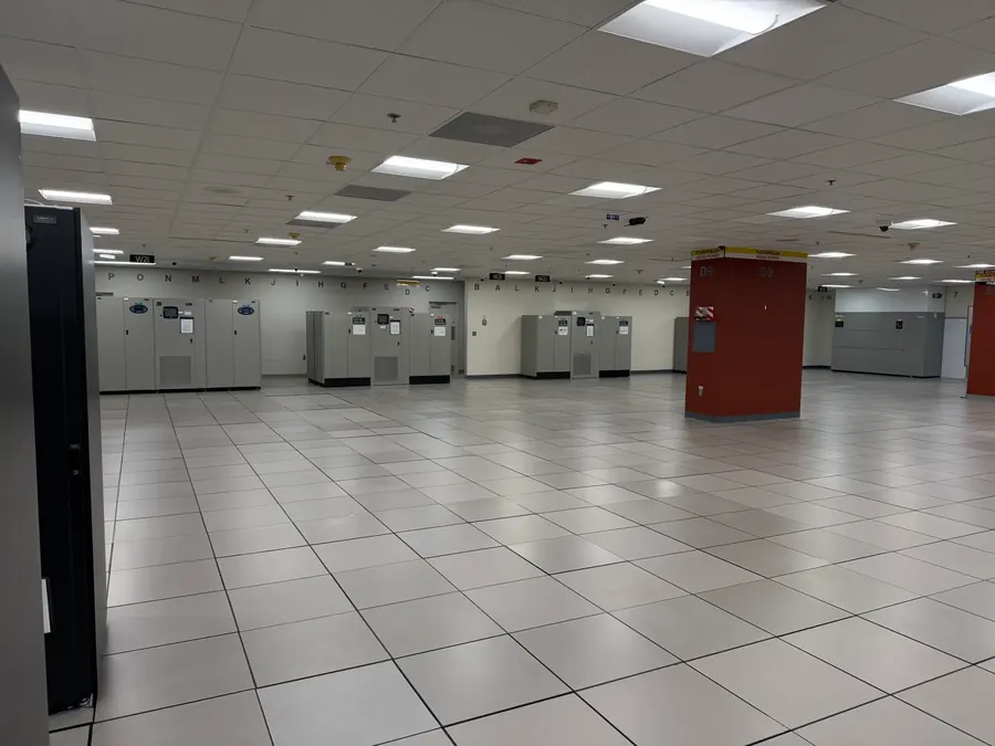 Open raised-floor data hall with lettered grid references and CRAH units around the perimeter